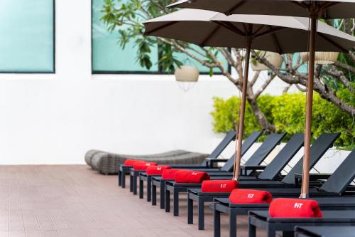 a row of blue and red chairs with an umbrella at Avani Khon Kaen Hotel & Convention Centre in Khon Kaen