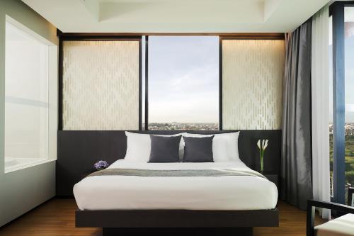 a bedroom with a large bed and large windows at Avani Khon Kaen Hotel & Convention Centre in Khon Kaen