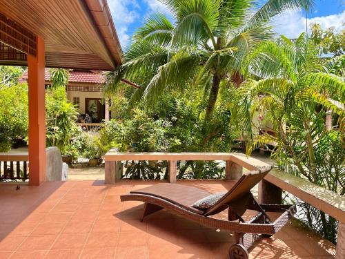eine Bank auf einer Terrasse mit Palmen in der Unterkunft Villa Dua - Beachfront Sunset Garden Villa in Nathon Bay