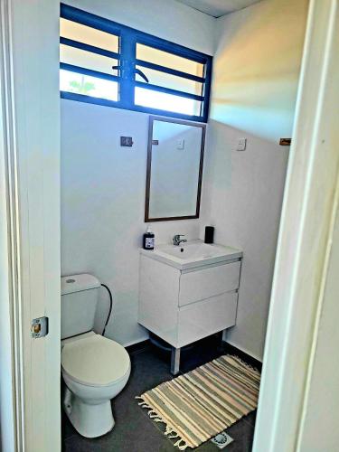 a bathroom with a white toilet and a sink at Teahupo'o Lodge Tahiti - Studio Tropical - climatisé - entre randonnées et activités nautiques in Teahupoo