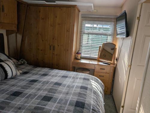 a bedroom with a bed and a desk and a window at Otter view in Garthbeibio