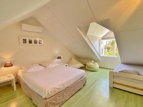 a attic bedroom with a bed and a window at Villa Perle des iles in F. Sauger