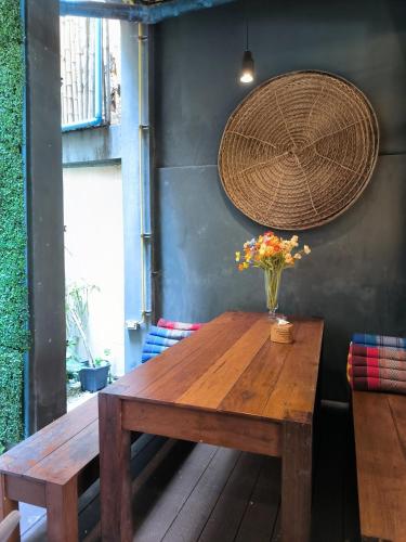 a wooden table with a vase of flowers on it at Whereder Poshtel in Udon Thani