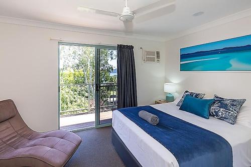a bedroom with a bed and a window and a chair at Sunset Waters 10 & Free Buggy - Hamilton Island in Hamilton Island