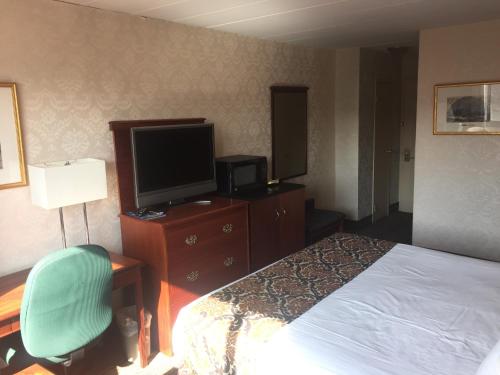 a hotel room with a bed, desk and television at Airway Inn in Queens