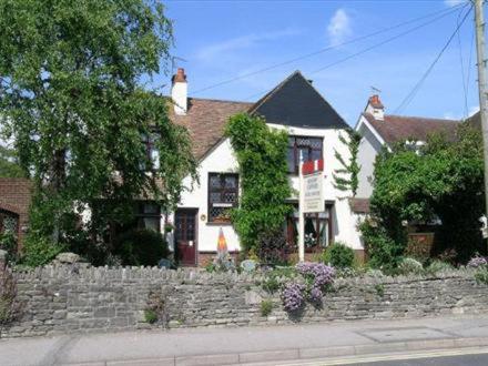 une maison blanche avec un mur en pierre devant elle dans l'établissement Railway Cottage, à Swanage