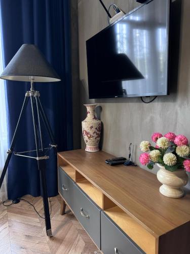 a desk with a television and a lamp and flowers at Bugu Hotel Bishkek in Bishkek