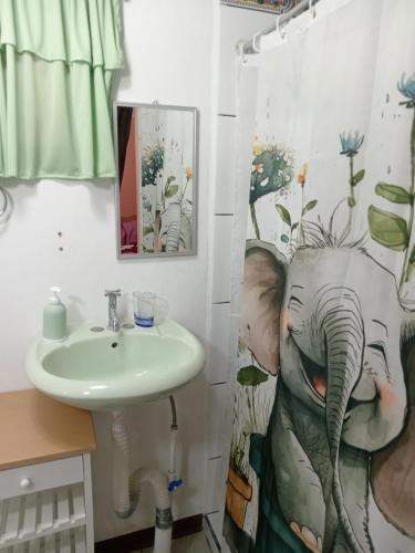a bathroom with a sink and an elephant shower curtain at Bowen apartamento in Quepos