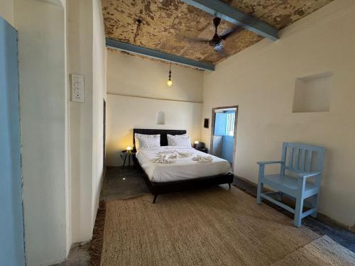 a bedroom with a bed and a blue chair at Rana Mahal - a Boutique Place in Varanasi