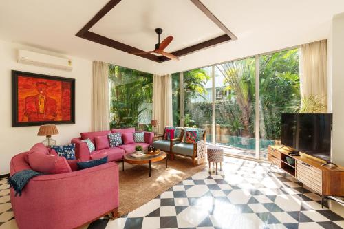 a living room with pink furniture and a flat screen tv at La Zamora, 3BHK Villas near Vagator & Anjuna Beach, North Goa with Private Pool, Garden, Terrace & Security in Assagao