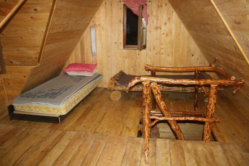 a room with a bed and a chair in a cabin at Holiday Park Zelenkovac in Podrašnica