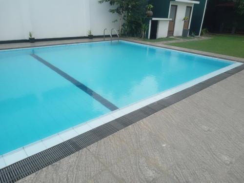 a swimming pool with blue water in front of a building at Blue Spring Hotel Wadduwa in Wadduwa