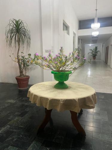 a green vase on a table with flowers on it at Hotel Los Proceres in La Aurora