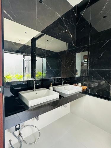 a bathroom with two sinks and a large mirror at บ้านไร่มีสุข Baanrai Meesuk in Surat Thani