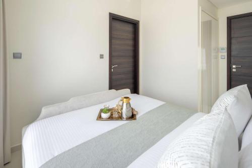 a white bed with a tray of food on it at Frank Porter - Albizia Damac Hills 2 in Dubai