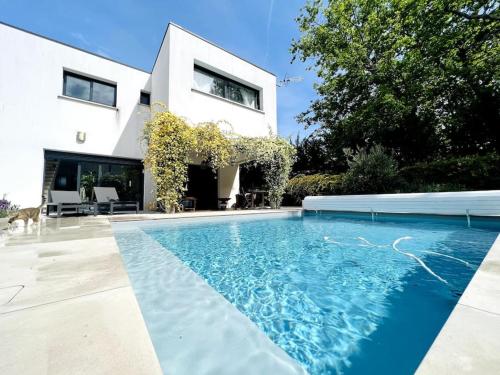 une maison avec une piscine devant une maison dans l'établissement Villa Poujeau - Piscine chauffée, à Le Pian-Médoc