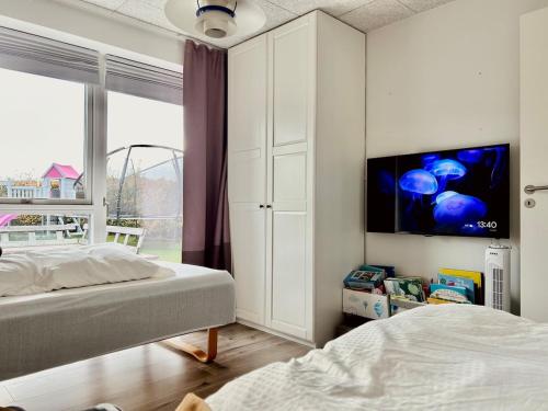 オーデンセにあるModern 3BR near Rosengård, City E20 & Congress Cのベッドが2つと壁にテレビがある寝室
