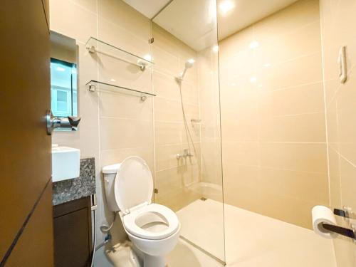 a bathroom with a toilet and a glass shower at BGC 1BR Condo Steps from Grand Hyatt #ournw18l in Manila