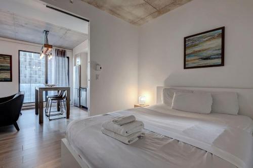 a white bedroom with a large bed with two towels on it at comfy studio in Old Port Montreal in Montréal