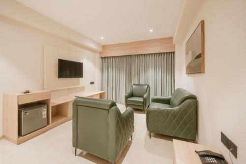 a living room with two chairs and a television at Loft Business Hotel in Kakkanad