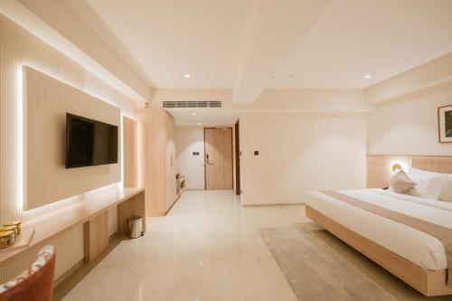 a bedroom with a bed and a flat screen tv at Loft Business Hotel in Kakkanad
