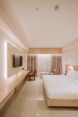 a hotel room with a bed and a tv at Loft Business Hotel in Kakkanad
