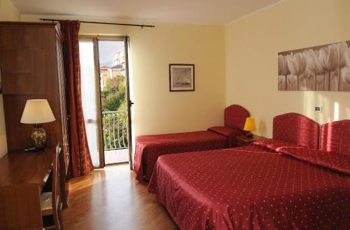 a hotel room with two beds and a balcony at Hotel Miranda in Varazze