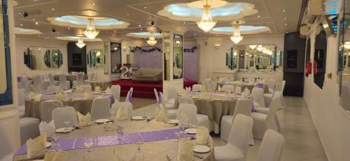 a banquet hall with white tables and white chairs at Nova Park Hotel in Sharjah