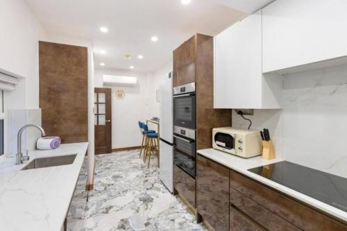 a kitchen with white cabinets and a sink and a microwave at Metro Majesty 5-Bedroom Gem in South Tottenham in London
