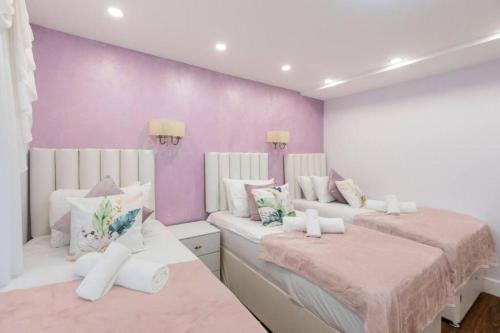 a room with two beds and a purple wall at Metro Majesty 5-Bedroom Gem in South Tottenham in London