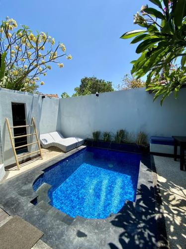 a small blue swimming pool next to a white wall at Stay Shark Villas Gili Air in Gili Islands