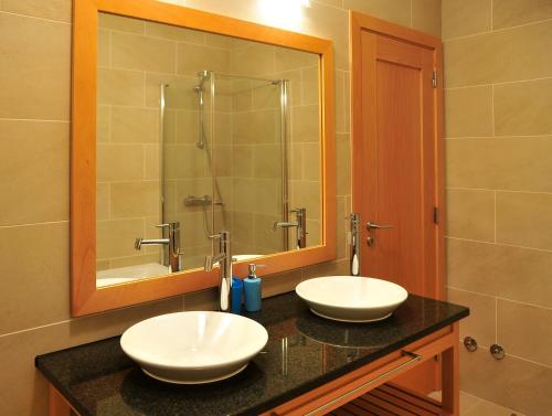 uma casa de banho com 2 lavatórios e um espelho grande em Praia Del Rey SeaView Dupplex em Praia del Rei