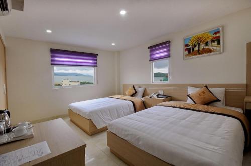 a hotel room with two beds and a desk at Yellow Sea Hotel Nha Trang in Nha Trang