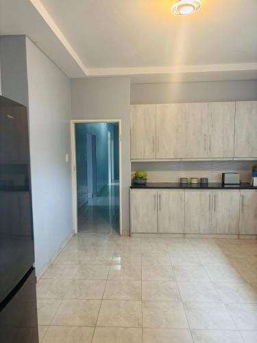 a kitchen with white cabinets and a tile floor at Mpande - The Roots Your Home Away from Home in Bulawayo