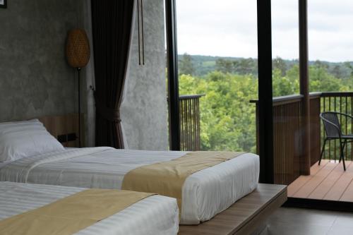 two beds in a hotel room with a balcony at Hug Jang Loei Garden & Resort in Ban Na Dan