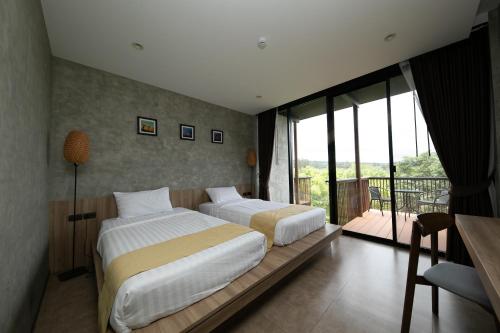 two beds in a hotel room with a balcony at Hug Jang Loei Garden & Resort in Ban Na Dan