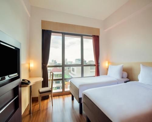 a hotel room with two beds and a large window at Asyana Kemayoran Jakarta in Jakarta