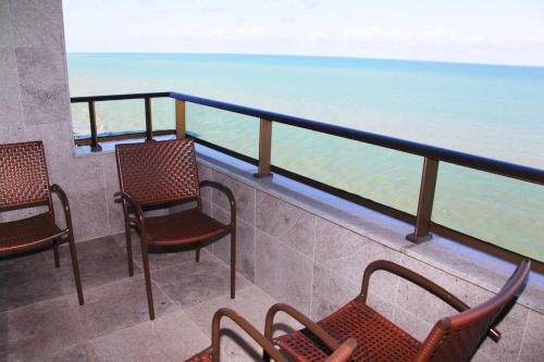 a balcony with chairs and a view of the ocean at Nobile Residences Maria Frazão in Recife