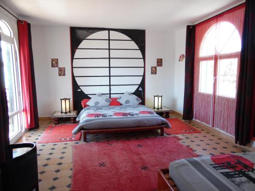 a bedroom with a large bed and a red rug at Villa Daba in Ghazoua