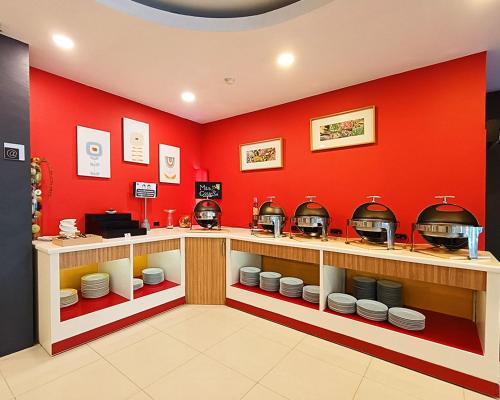 a restaurant with red walls and a counter with dishes at Asyana Kemayoran Jakarta in Jakarta