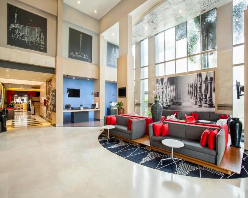 a lobby with a black couch and red pillows at Asyana Kemayoran Jakarta in Jakarta