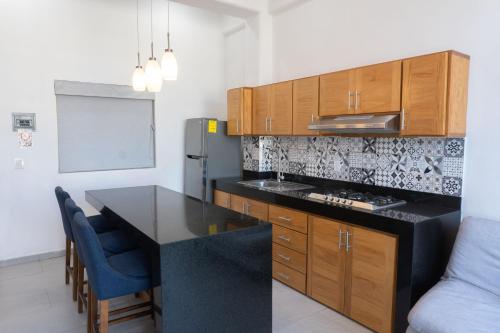 a kitchen with a black counter top and wooden cabinets at Hotel y Departamentos Sofia in Rincon de Guayabitos