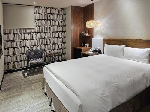 a bedroom with a large white bed and a chair at CHECK inn Yilan LuoDong in Luodong