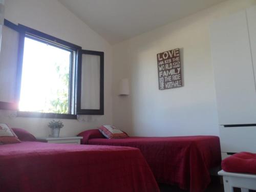 a room with two beds with red sheets and a window at Nachetes 1 in Cala Blanca