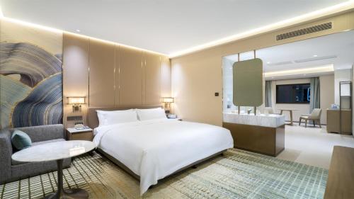 a bedroom with a white bed and a living room at Victoria Hotel Guangzhou Zhujiang New Town - Free shuttle bus during Canton Fair period in Guangzhou