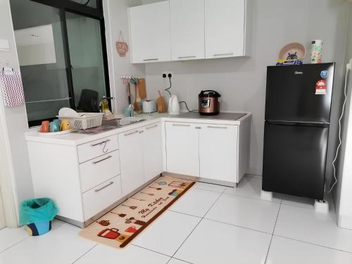 a kitchen with white cabinets and a black refrigerator at Paradigm Mall Platino Apartment 2BR 2FREE By Natol in Johor Bahru