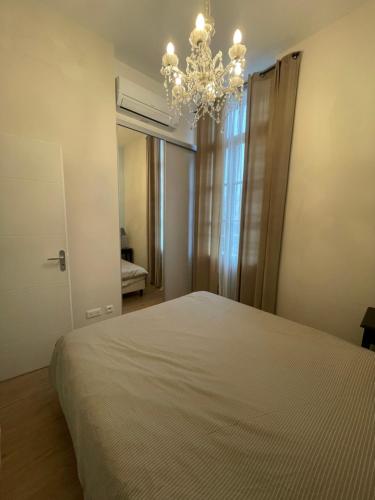 une chambre avec un lit et un lustre dans l'établissement Emplacement rare élégant appartement avec balcon sur le Canal Royal, à Sète