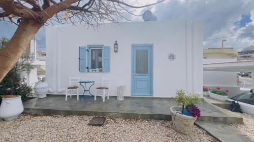 a white house with a blue door and a table and chairs at ''TSI TSI' traditional home & private Pool' in Kalithies