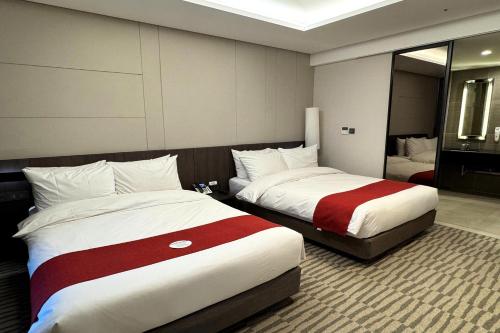 a hotel room with two beds and a mirror at Best Western Plus Jeonju in Jeonju