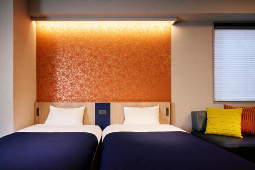 two twin beds in a room with a wall at Minn Nihonbashi in Tokyo